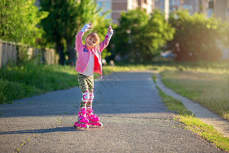 穿着粉色滚滚机和粉红色毛衣的小女孩在公园里装扮 微笑着笑 运动 户外活动图片