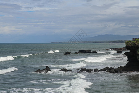 巴厘岛海岸附近印度洋的岩石悬崖 靠近和旅游景点海神庙 波浪在凝固的黑色火山熔岩的岩石上破碎 印度尼西亚 假期 旅行图片