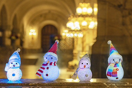 小雪人穿着彩虹围巾和帽子 与金色的光耀眼对抗 等待圣诞时光和礼物 玩具 快乐的图片