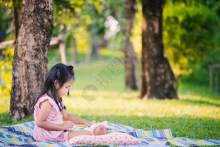 一个可爱的小女孩 读一本书 坐在树下 坐着图片
