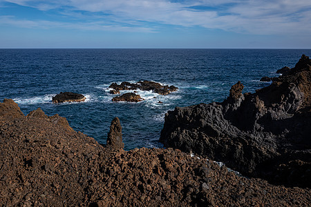 火山岩层形成 岩石海岸的黑熔岩悬崖 天空 海浪图片