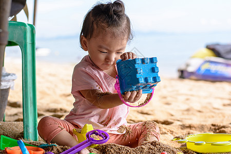 在海滩上玩沙滩玩具的可爱小女婴图片
