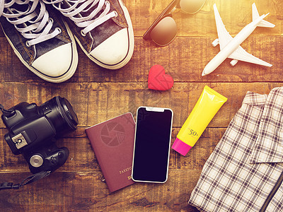平躺的护照 手机 飞机模型 运动鞋 钱包 相机和旅行者的配件物品在木制背景上带有复制空间 旅行和度假的概念 指导 娱乐图片