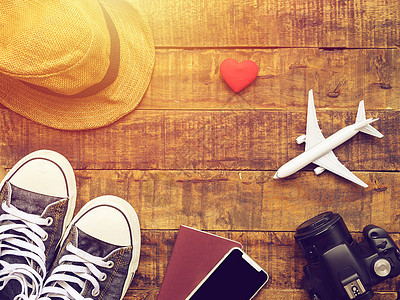 平躺的护照 手机 飞机模型 运动鞋 电话 相机和旅行者的配件物品在木制背景上带有复制空间 旅行和度假的概念图片