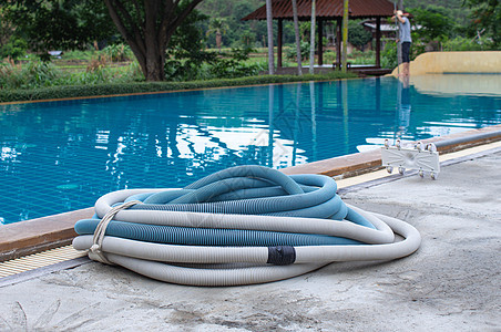水泥地板上的游泳池真空吸尘器软管清洁水池的手动设备 工具 职员图片