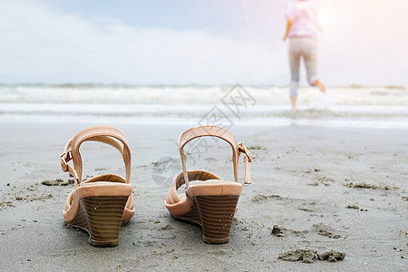 海滩假期旅游度假生活方式概念-快乐的中年商务女士脱鞋跑入大海 赤脚享受美丽的海滩图片