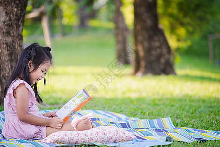 一个可爱的小女孩 读一本书 坐在树下 学校图片
