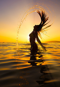 日落时女人在海中翻头发图片
