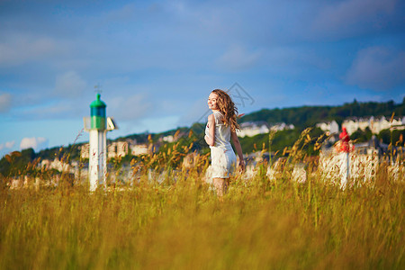 在灯塔附近的草地上 日落时的年轻女子图片
