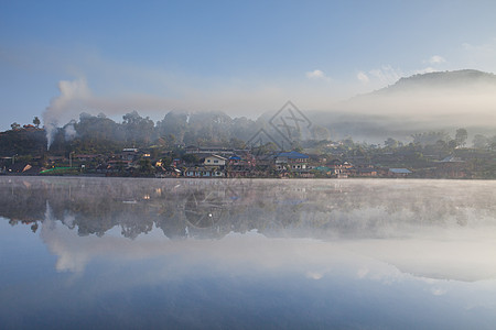 高山风景 云云下村庄和山丘对水的反光 商业图片