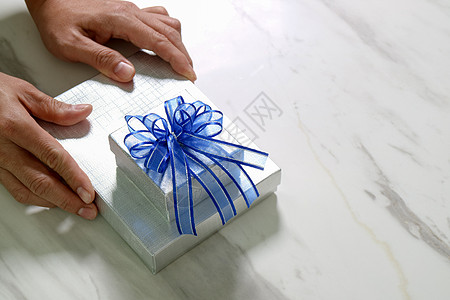 男子手拿着礼物盒作为赠与的表示 b 蓝色的 丝带图片