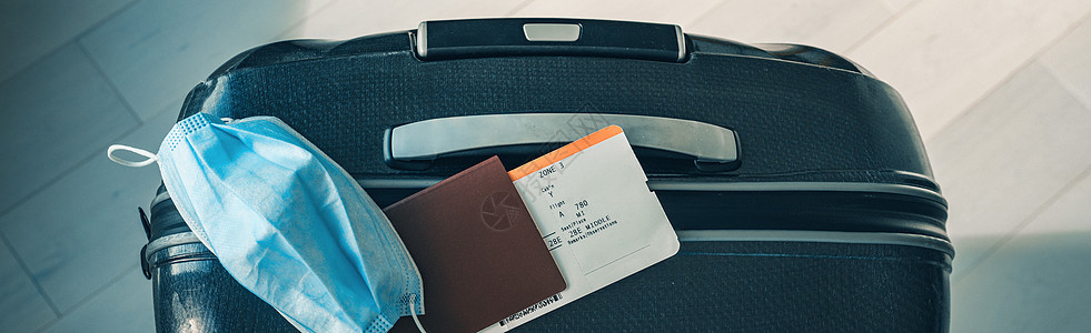 由于在机场和飞往欧洲 亚洲的飞机航班上必须佩戴电晕病毒面具 COVID-19 旅行受到限制 护照 机票和手提箱准备好度假 全景横图片