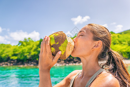 椰子水加勒比热带食品旅游女性在游轮旅行度假时从椰子中饮用新鲜天然 享受暑假的亚裔女孩图片