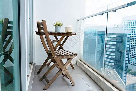 阳台上的木桌和椅子 俯瞰着现代大城市 舒适的阳台图片