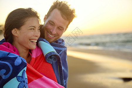 在沙滩日落时 喜笑着浪漫的混合种族情侣图片