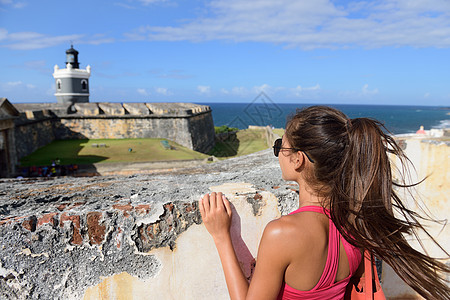 波多黎各在圣胡安旅游的女游客 俯视着美国波多黎各老圣胡安市的著名景点卡斯蒂略圣费利佩德尔莫罗堡 暑假图片