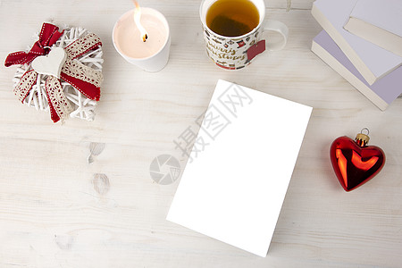 从顶部看一本书的圣诞景色 空白封面的书 上面点着白蜡烛 圣诞装饰的茶杯 红心摆设 浅色木桌上装饰破旧的白心 庆典 花环图片
