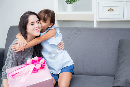 漂亮妈妈喂奶以粉红丝带为礼物的亚西安人母亲和女儿快乐 展示 惊喜背景