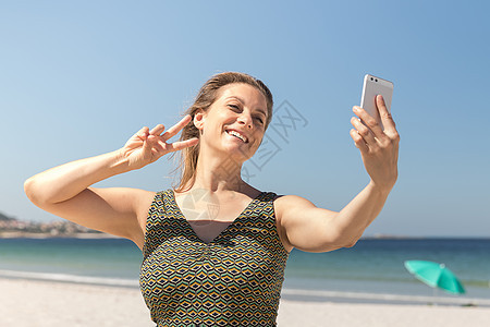 穿着绿裙子的中年金发女郎 在海滩上拍自拍图片