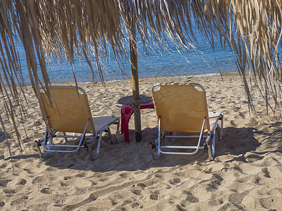 在希腊沙滩上用太阳雨伞 关闭两座黄色空的阳光床 并装有绿绿绿色清蓝海水 海岸 热带图片