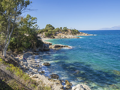 从希腊科孚岛卡西奥皮的小径可以看到巴塔里亚白色沙滩 蓝色日光浴床和游客在卡西奥皮湾以及阿尔巴尼亚山脉 海景 旅行图片