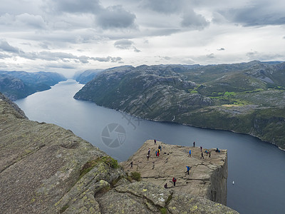 巨大的悬崖在峡湾 Lysefjord 著名的挪威观点与游客和徒步旅行者 喜怒无常的秋日 自然和旅游背景 假期和远足假期的概念 全图片