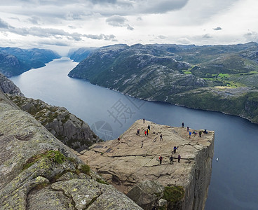 巨大的悬崖在峡湾 Lysefjord 著名的挪威观点与游客和徒步旅行者 喜怒无常的秋日 自然和旅游背景 假期和远足假期的概念 秋图片