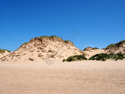 沙丘覆盖着粗草和蓝色的夏日天空 高高的沙丘被遮盖在青草丛中图片