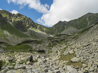 背着背包远足小径的男子徒步旅行者在山谷与岩石巨石 灌木松和绿色山峰 西塔特拉山脉 Rohace 斯洛伐克 夏天 蓝天背景图片