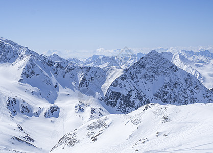 从滑雪区的山顶的冬季风景 在阳光明媚的春日有雪覆盖高峰 蓝天背景图片