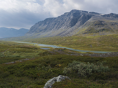 美丽的野生拉普兰自然景观 有蓝色冰川河流 白杨树丛 雪盖山峰和戏剧性云层 瑞典北部Kungsleden远足小道的夏季瑞典北部 蓝图片