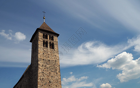 古老的石教堂塔 在戏剧性的蓝云背景上图片