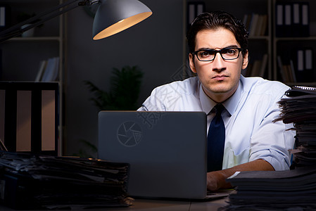青年商人在办公室加班加班时间工作; 电脑 小时图片