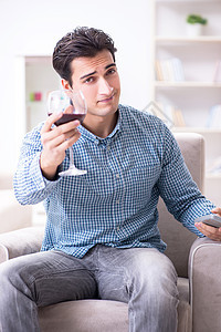 年轻男人在家喝葡萄酒 欢呼 午餐 享受 电视 玻璃背景图片