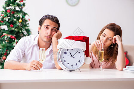 年青夫妇在家里庆祝圣诞日 假期 伤心 女士 钟图片