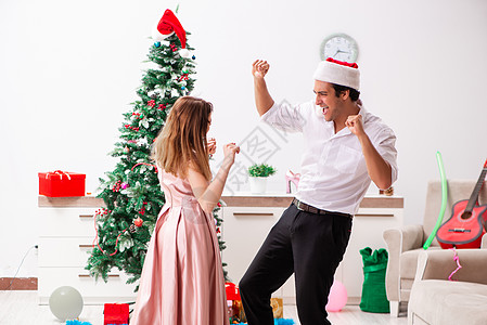 年轻一对在家里庆祝圣诞节的年青夫妇 树 裙子图片