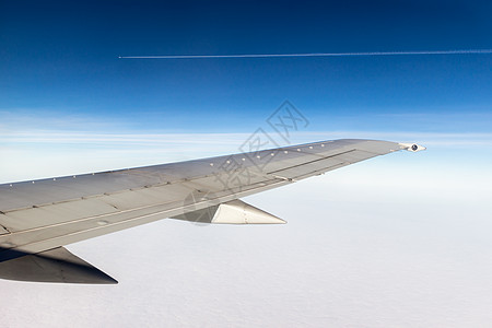蓝天空背景的飞机机翼 翅膀下云层 平行平面与足迹相距很远图片