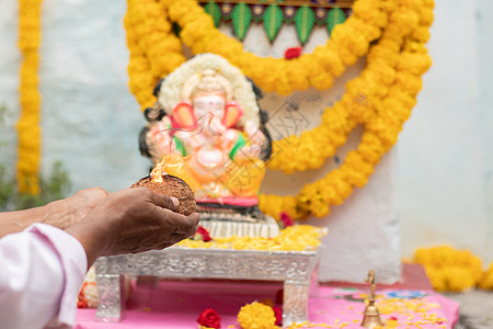 在印度的维那亚卡查图尔提节期间提供阿蒂 aarti 或在家里庆祝 为敬拜Ganesh领主的手贴近了图片