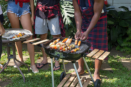 男人在烤烤烤肉烧烤炉上做饭 为家庭后院派对 周末 制作图片
