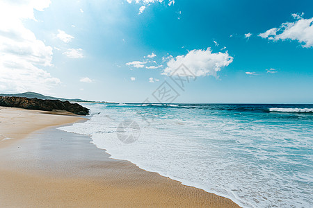 阳光明媚的一天 海浪席卷着海浪进入沙滩的大片荒野海滩 天空超亮图片