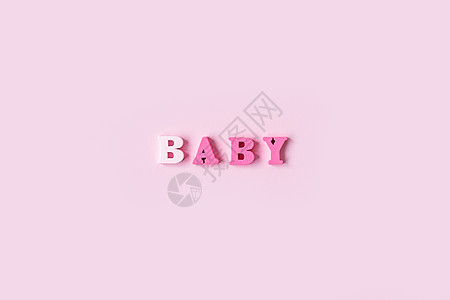 BABY 这个词是由浅粉色背景上的木制字母组成的 横幅设计 婴儿淋浴概念 最小背景的照片 装饰精美 文本位置与粉红色背景隔离图片