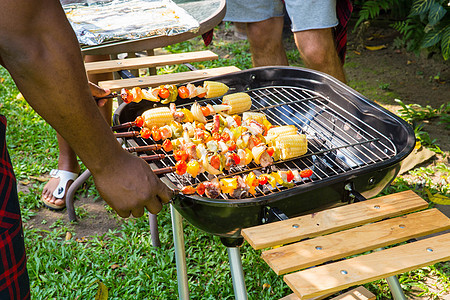 男人在烤烤烤肉烧烤炉上做饭 为家庭后院派对 食物 花园图片