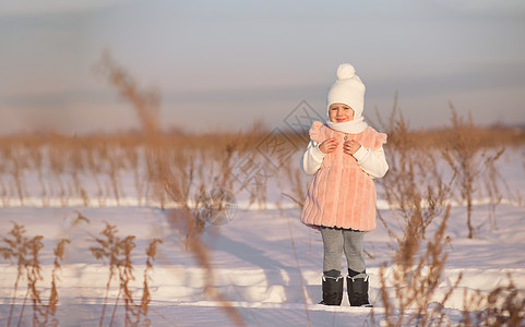 一个小女孩站在田地中间 在日落的冬天 在一个寒冬 快乐 自然图片