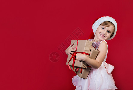 可爱可爱的笑笑女孩 带着圣诞礼物 在红色上被孤立 圣诞节 假期图片