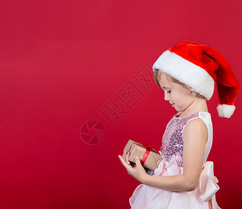 可爱可爱的笑笑女孩 带着圣诞礼物 在红色上被孤立 惊喜 圣诞节图片