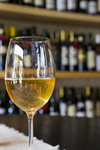 餐桌上满满的白酒杯 酒瓶背景 葡萄酒杂志以及餐馆和酒吧的商店 咖啡店 金的图片