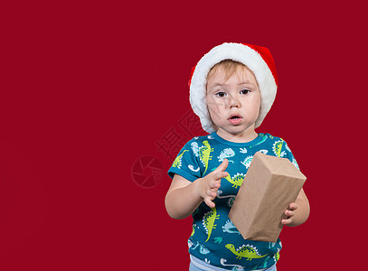 一个小男孩想把新年礼物拆包 看着镜头看背景图片