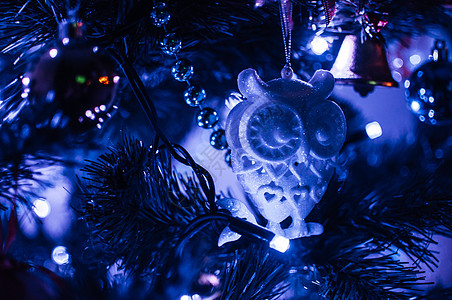 在霓虹蓝光中装饰的圣诞树特写镜头 玩具玻璃猫头鹰和带灯笼的花环 新年的小玩意微距照片与散景 寒假灯光装饰图片