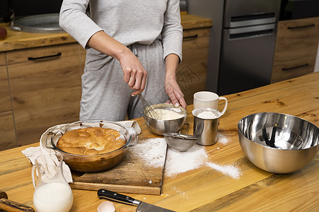 橡木桌上的美味苹果派 配料 穿着灰色睡衣的女人在阁楼风格的厨房里做美味的苹果派 牛奶 鸡蛋 糖和桌上的烤馅饼 家庭厨房 甜的 面图片