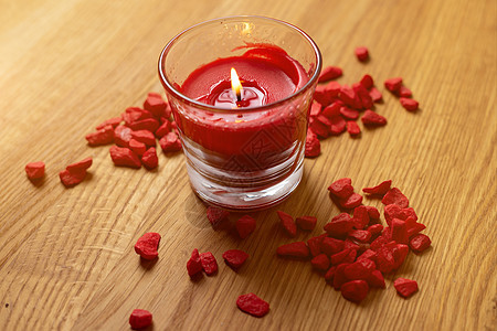 红蜡烛在木制桌子上用玻璃装着图片